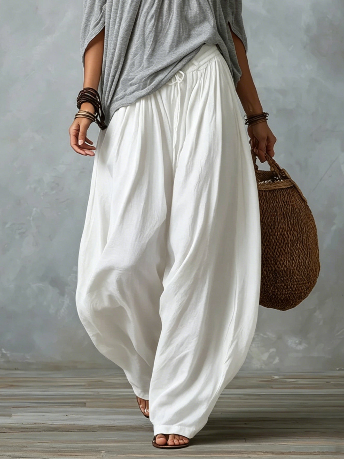 Top grigio con spalle scoperte e completo con pantaloni bianchi ampi a lanterna